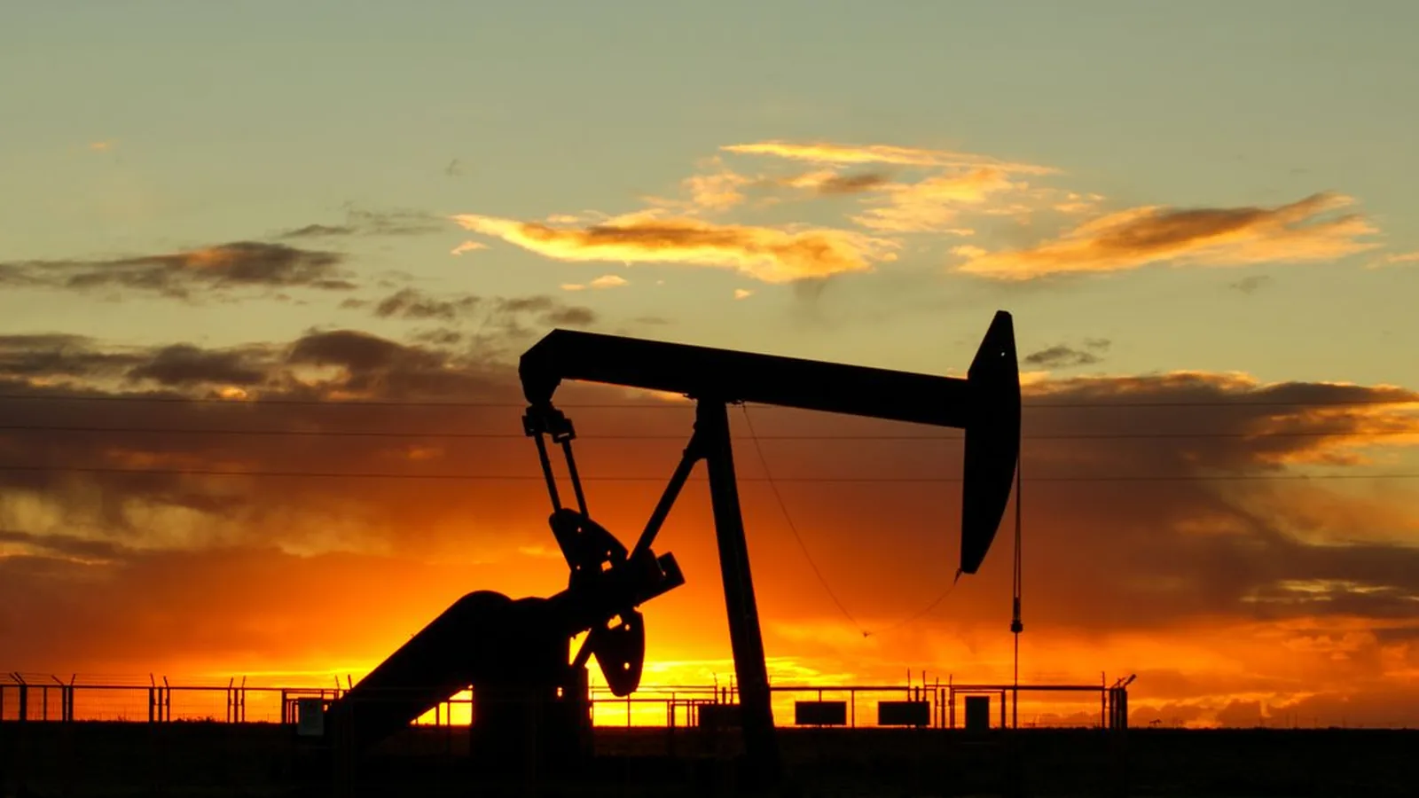 Силуэт нефтяной качалки на фоне яркого закатного неба