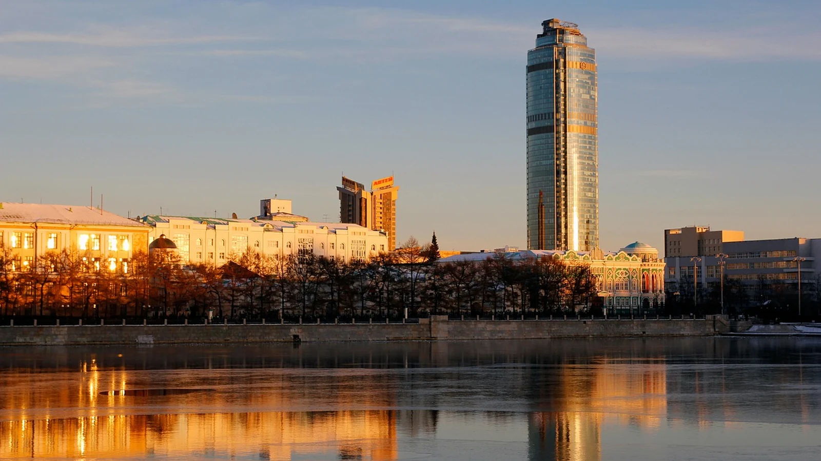 Закат над прудом в Екатеринбурге, в воде отражаются здания и высотный небоскрёб
