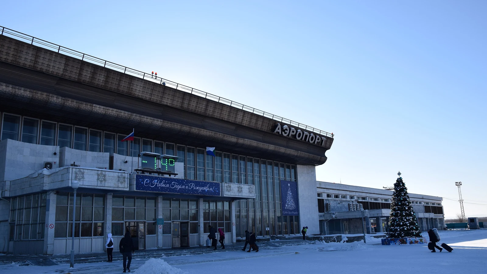 Здание аэропорта Хабаровск зимой, снег на площади перед входом и ясное голубое небо